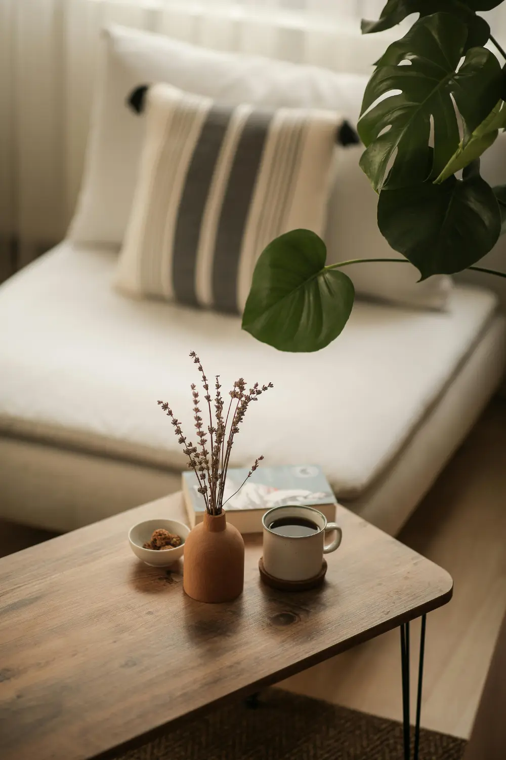Cozy coffee table vignette with a mug, vase, and greenery in a small neutral living room, demonstrating how to create quiet luxury in a small space.