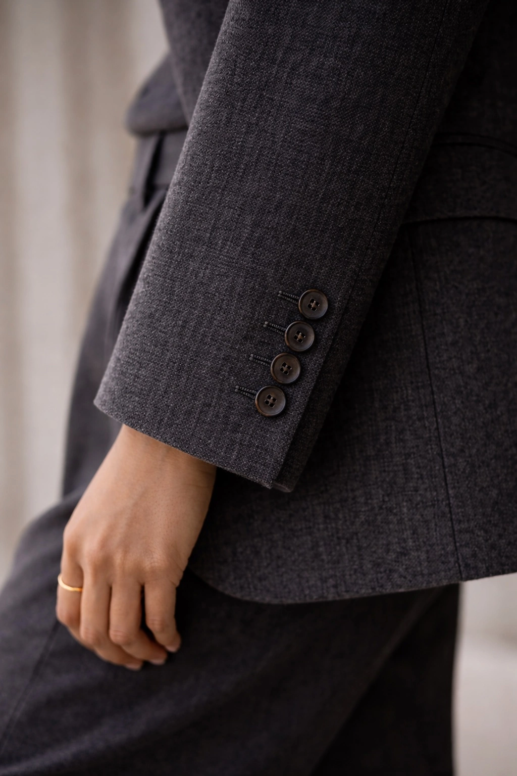 Close-up of tailored cuff in charcoal fabric-quiet structure that keeps a work outfit polished and comfortable.