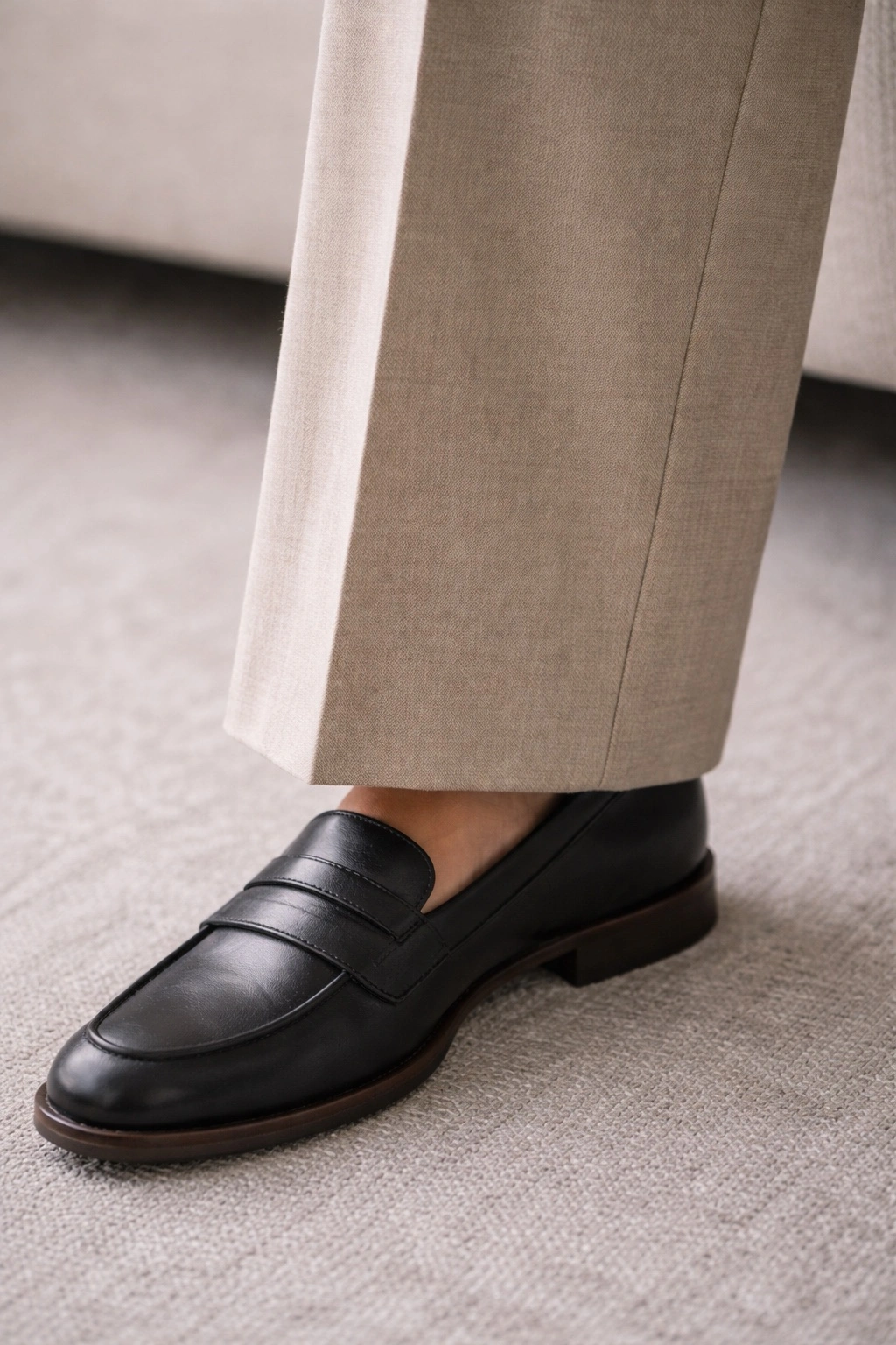 Close-up of tailored trousers falling cleanly over a flat leather loafer, showing proper hem length and fabric weight.