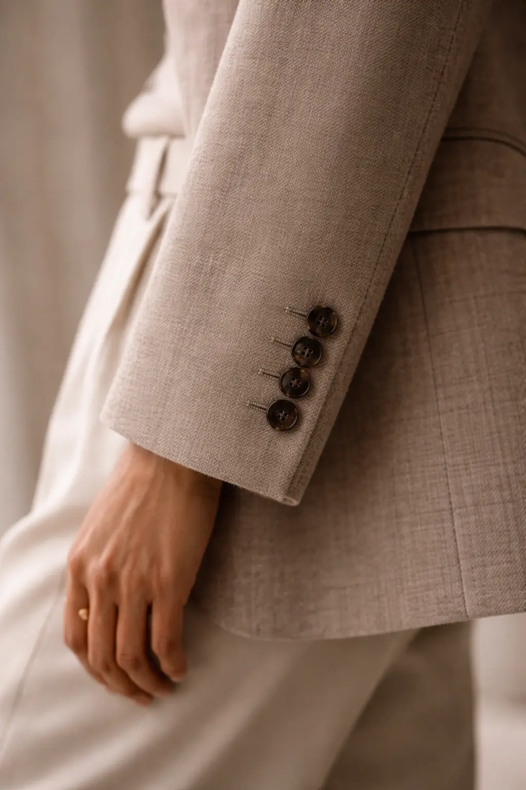 Detailed shot of a blazer cuff, respresentative of the quiet signals of quiet luxury that can elevate basics.