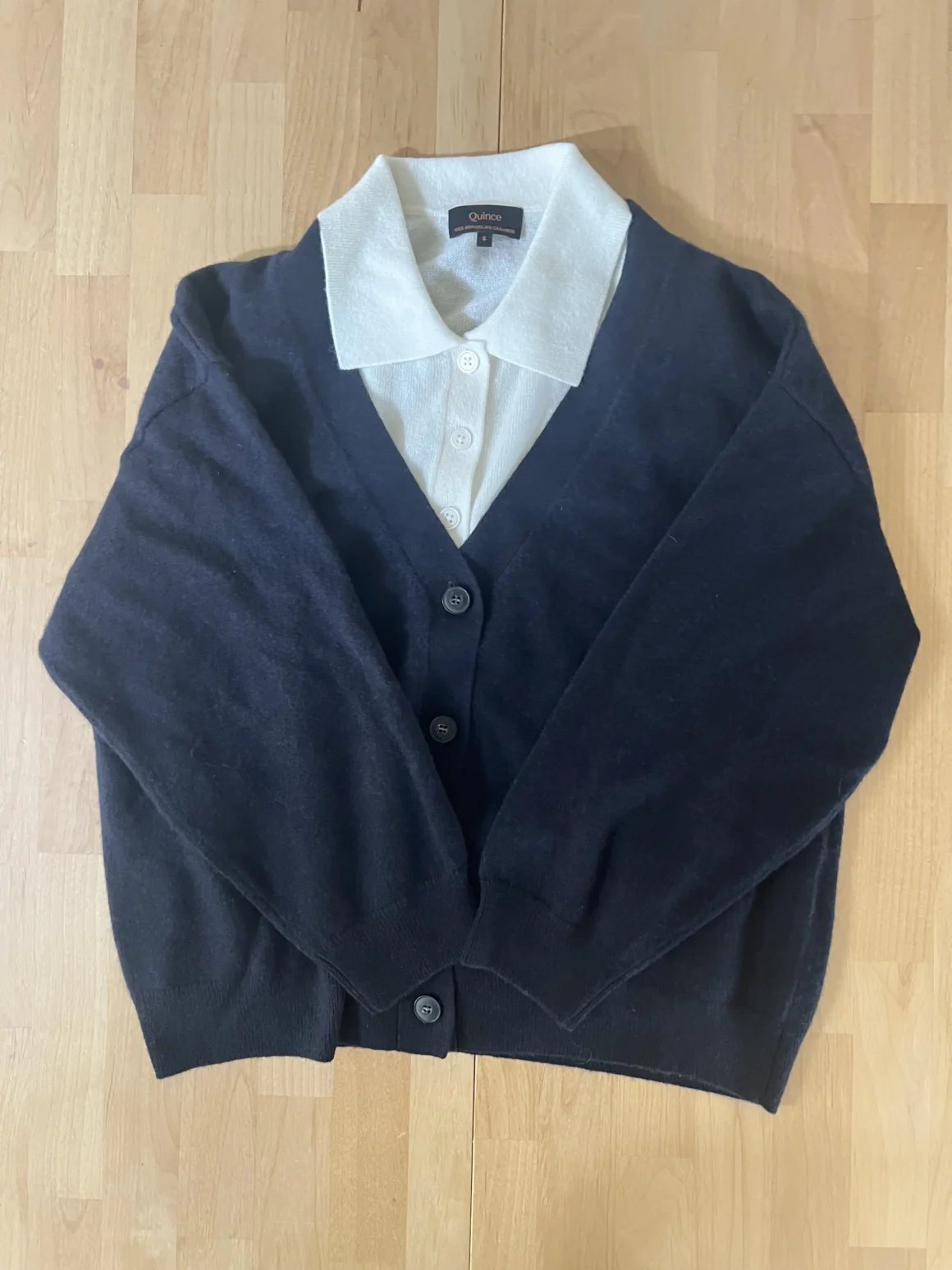 A white quince polo beneath a navy Naadam cardigan, an example of repeating the same clothes in various ways.